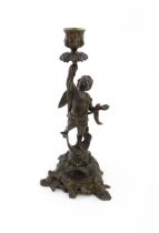 An early 20thC cast candlestick modelled as a winged putto / cherub holding aloft a sconce with