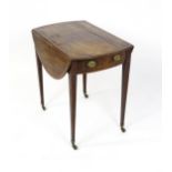 An early 19thC mahogany Pembroke table with a crossbanded top and two demi lune leaves above a