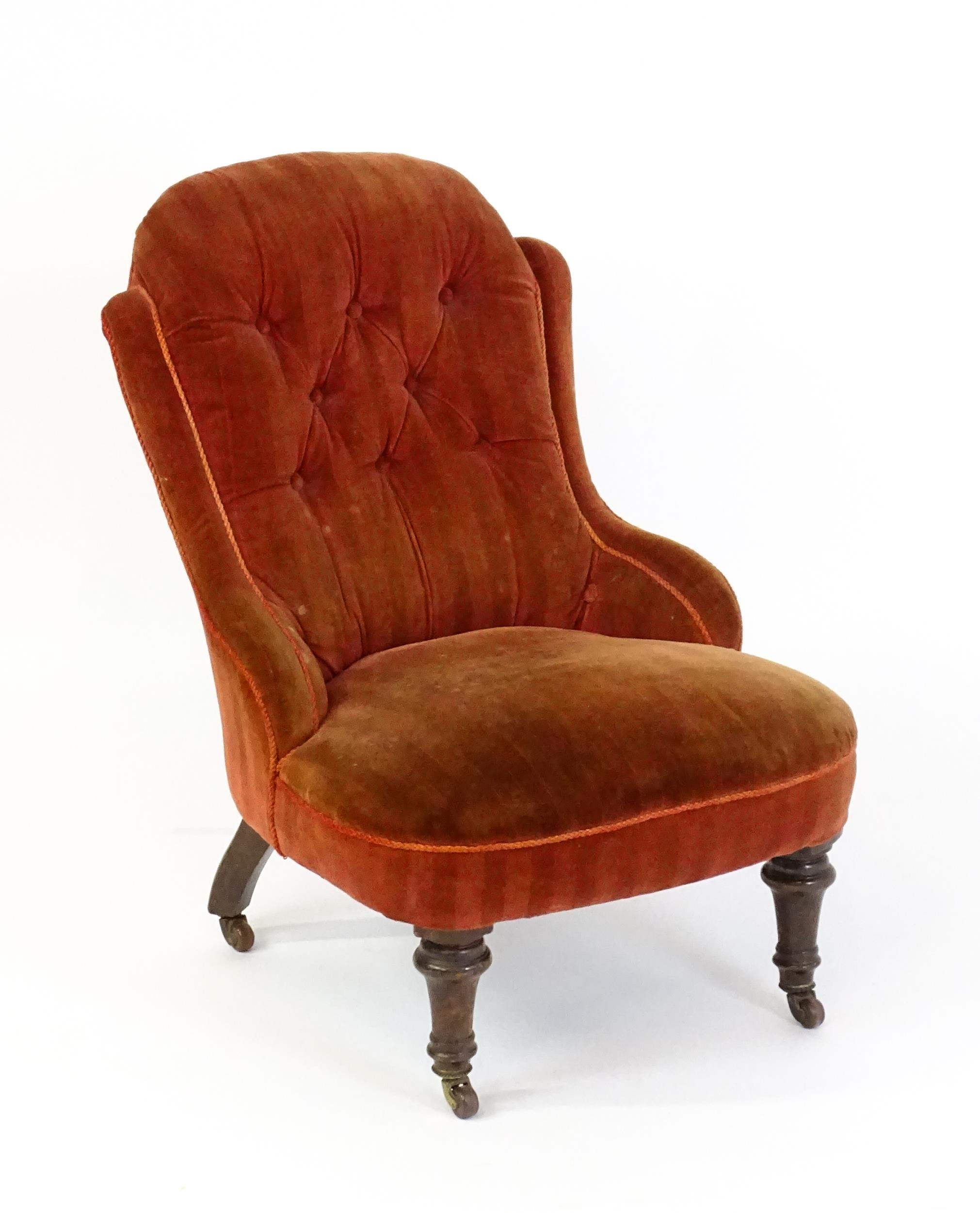 A late 19thC / early 20thC nursing chair with a deep buttoned backrest, sprung seat and raised on