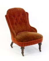 A late 19thC / early 20thC nursing chair with a deep buttoned backrest, sprung seat and raised on