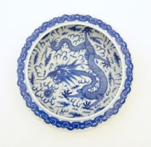 A Chinese blue and white bowl / dish decorated with a dragon and flaming pearl amongst stylised