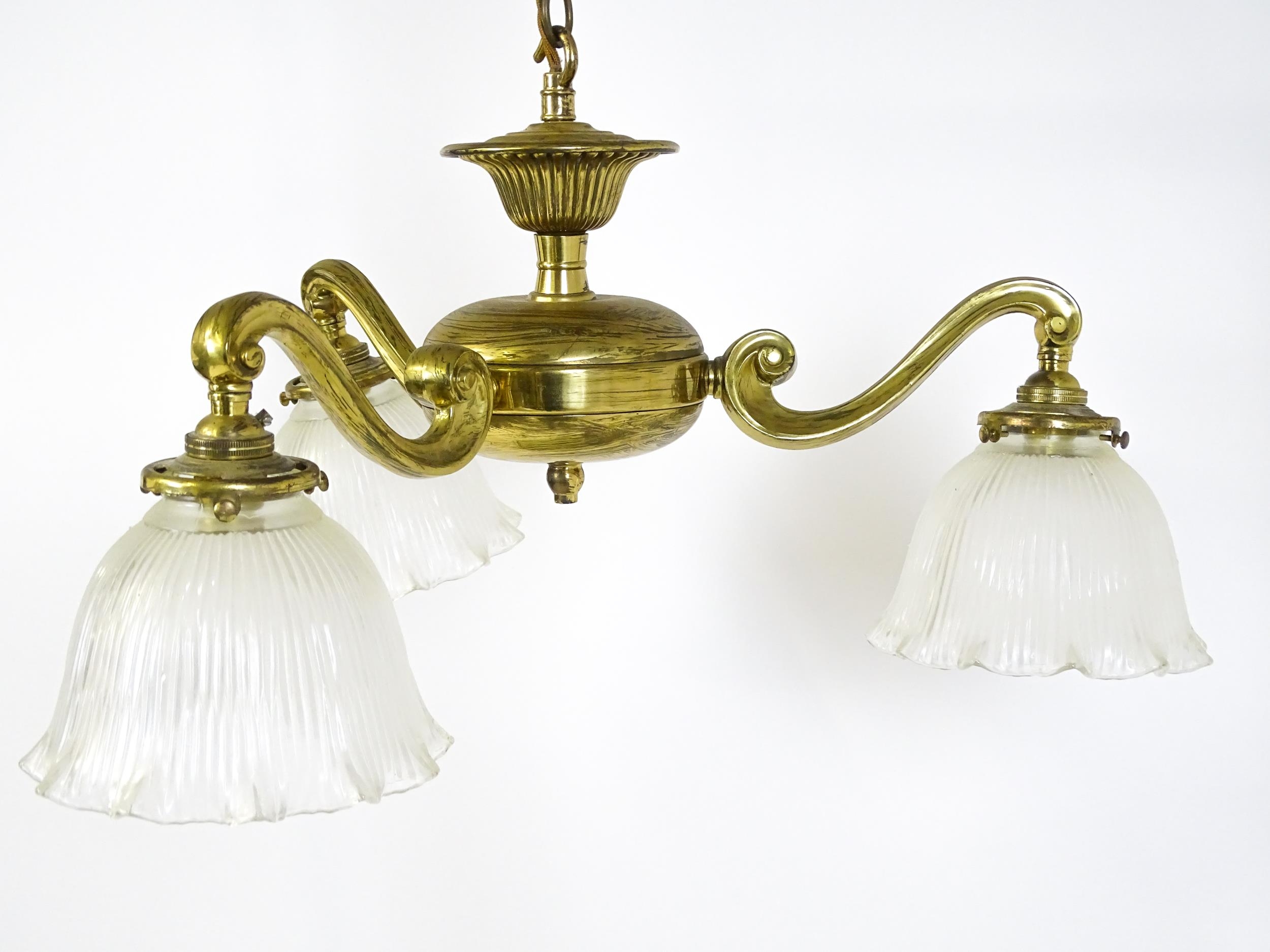 A pair of brass pendant lights having three scrolling branches with three holophane shades. - Image 6 of 16