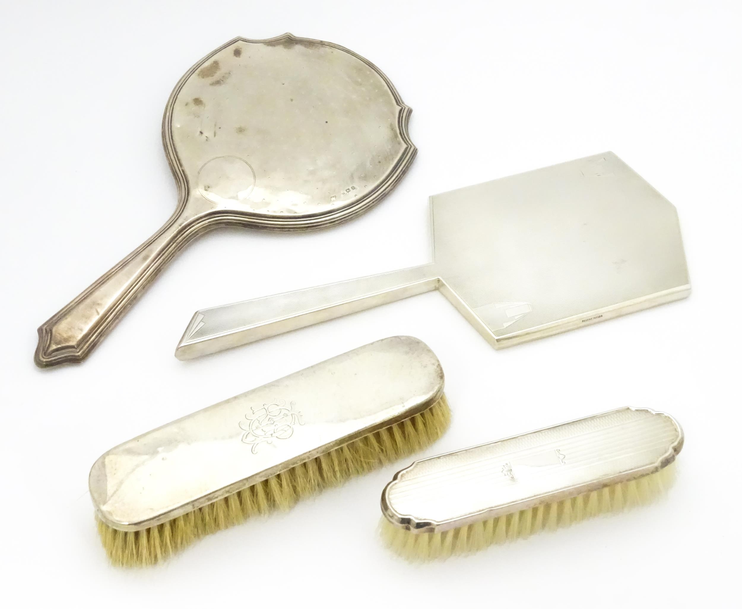 Four assorted silver backed dressing table items to include two brushes and two mirrors, to