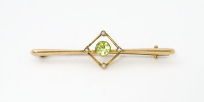 A 9ct gold bar brooch set with central peridot and four seed pearls. Approx 2" wide Please Note - we