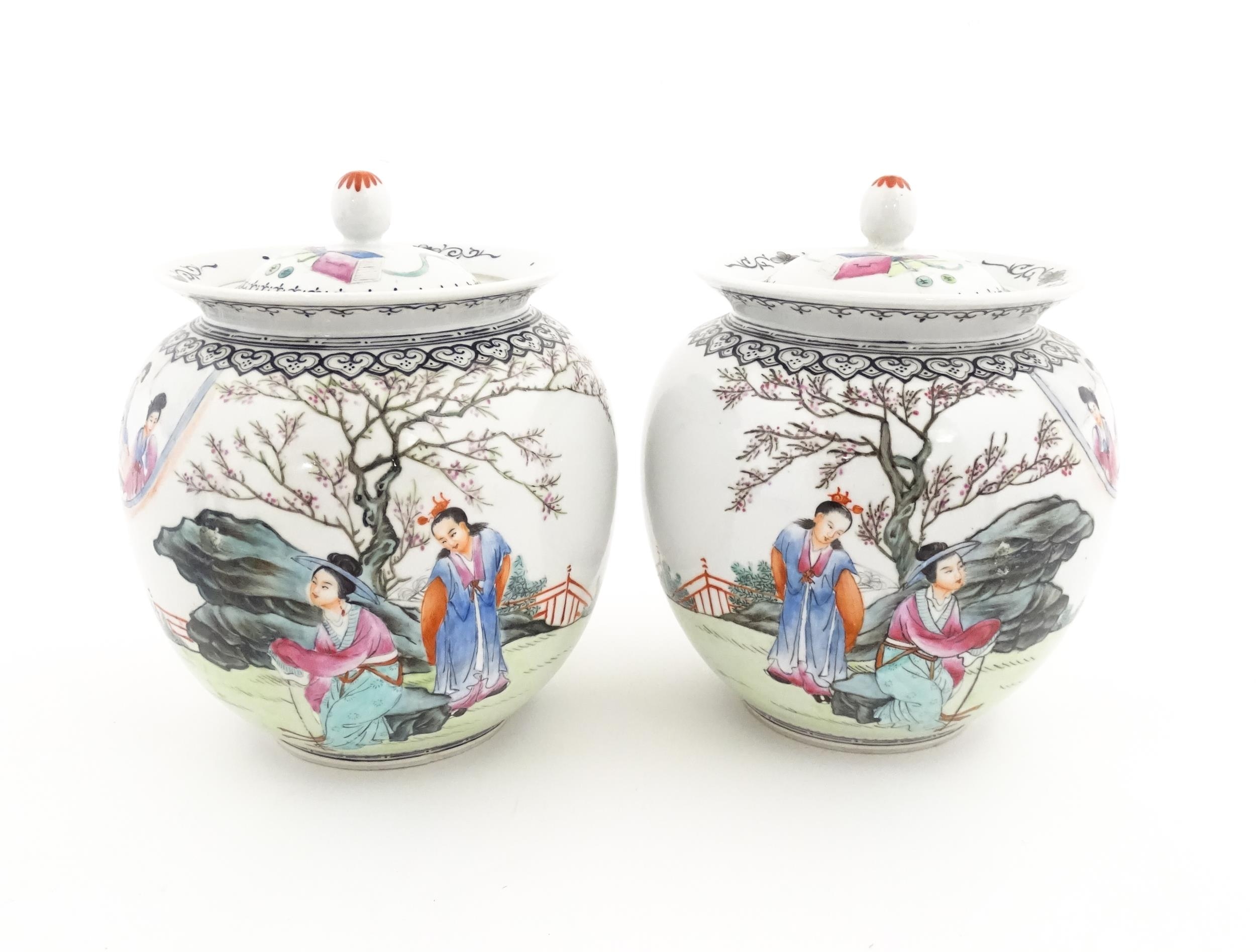 A pair of Chinese pot and cover vases decorated with ladies in a landscapes, and Character script.