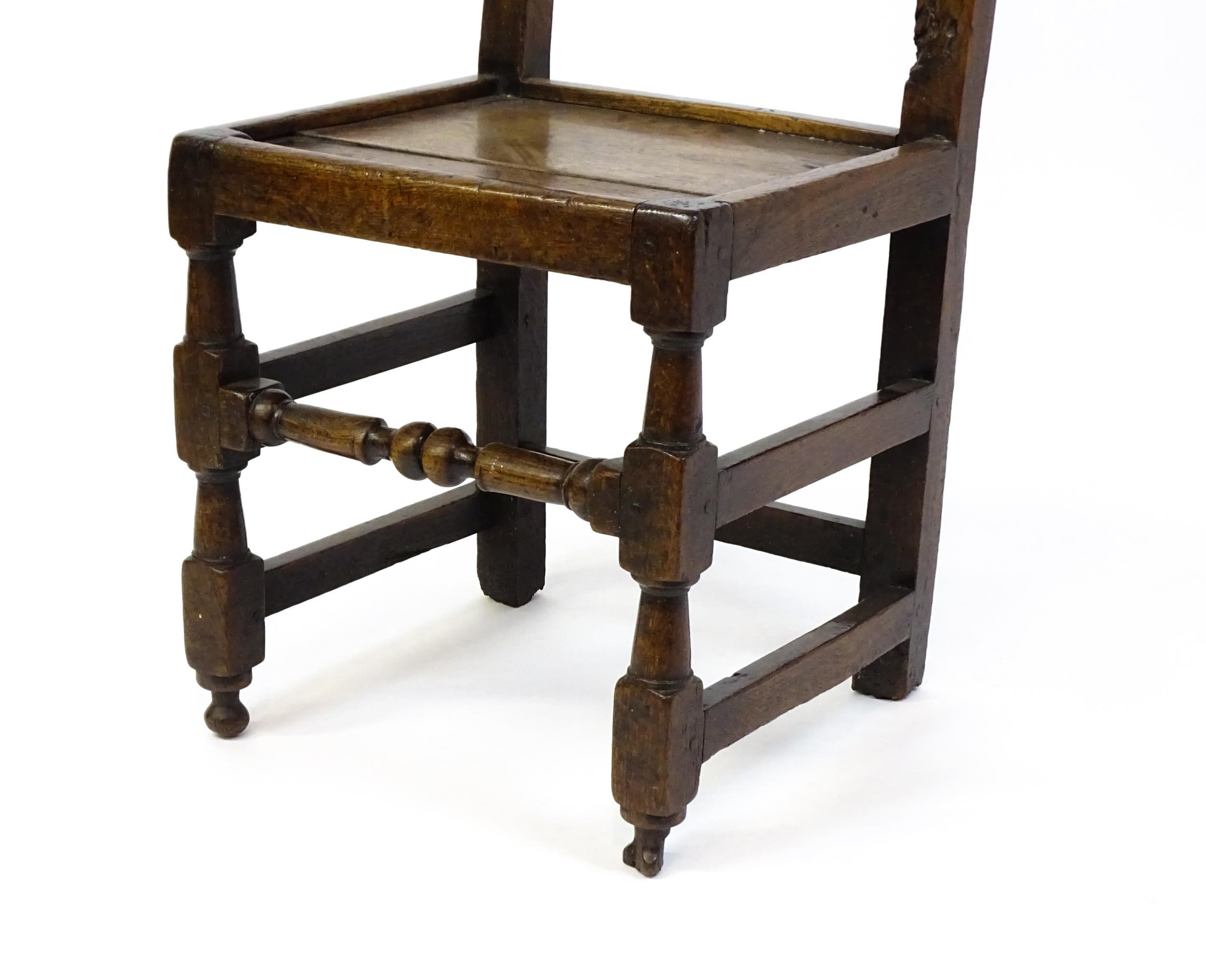 A 17thC oak peg jointed hall chair / back stool with a carved and scrolled top and mid rail raised - Image 7 of 7