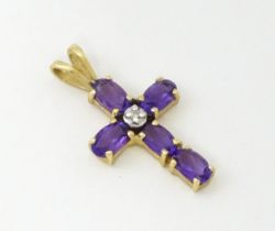 A 9ct gold cross formed pendant set with amethyst and central diamond. Approx. 1" long Please Note -