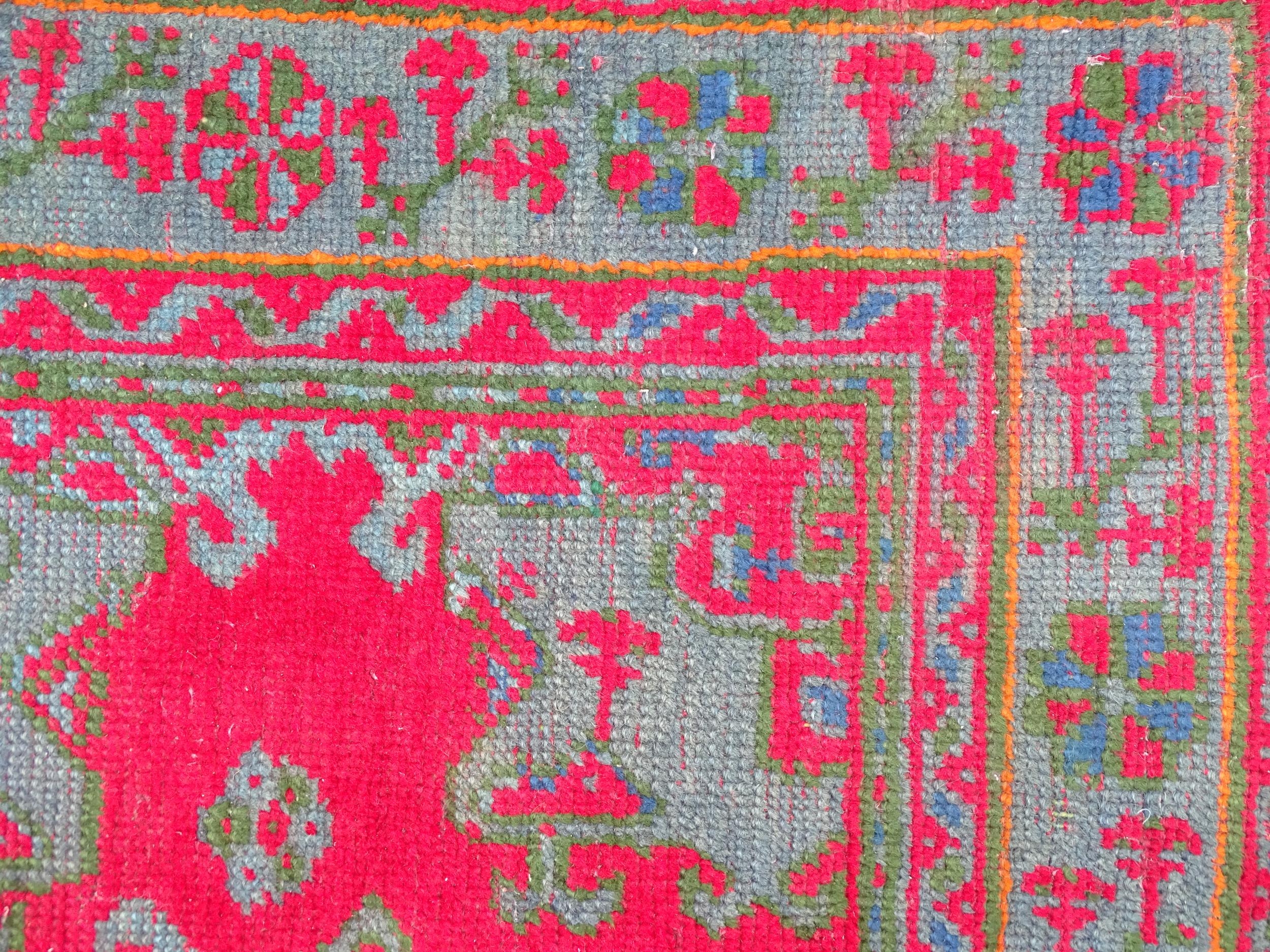 Carpet / Rug : A red ground rug decorated with floral, foliate and geometric detail worked in blue - Image 4 of 7