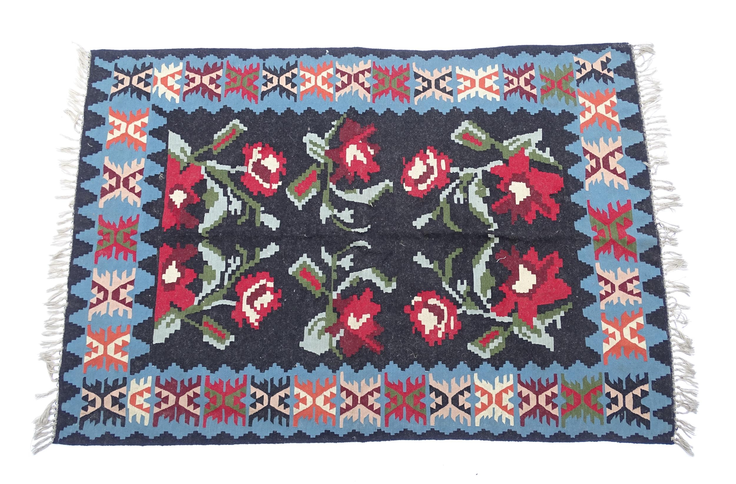 Carpet / Rug : A black ground rug with red floral decoration, with geometric motifs to borders.