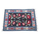 Carpet / Rug : A black ground rug with red floral decoration, with geometric motifs to borders.
