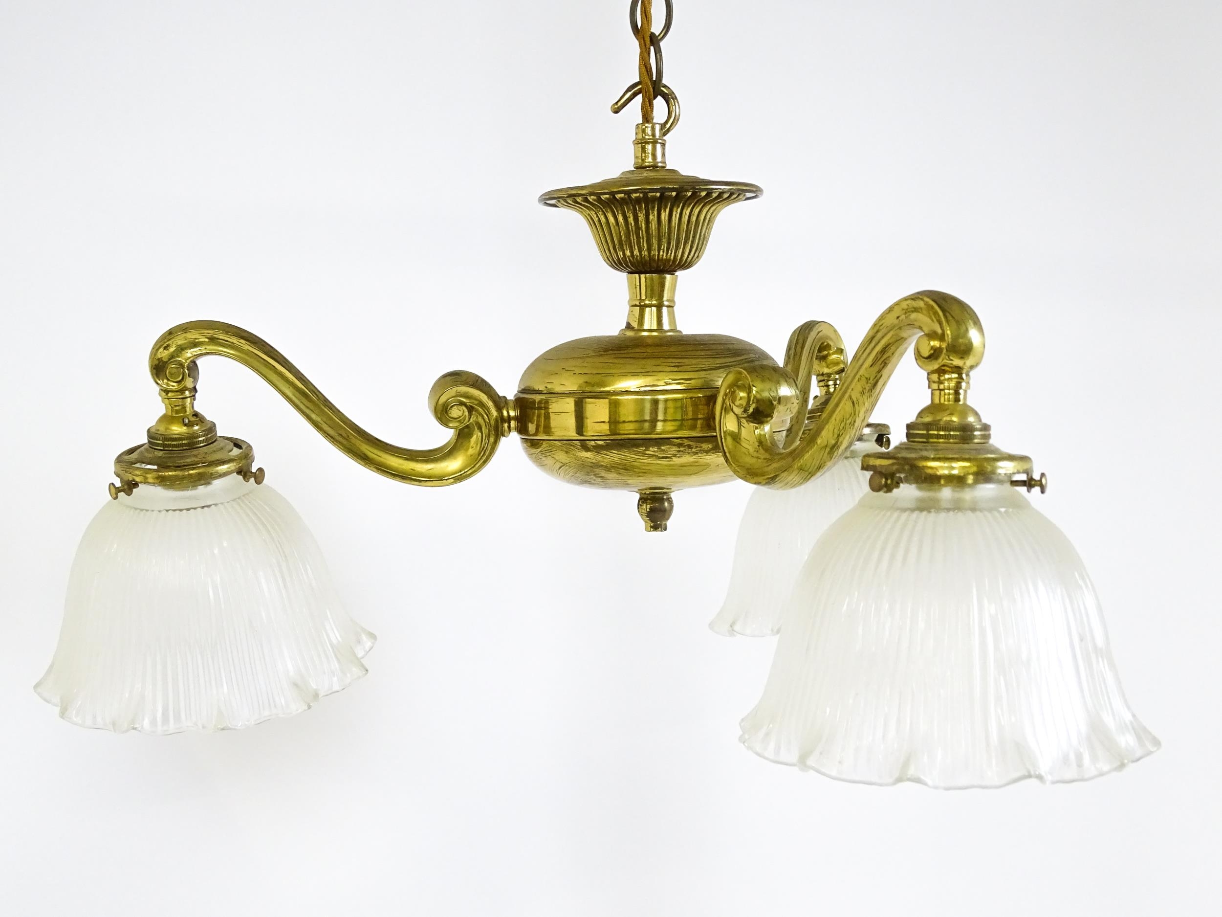 A pair of brass pendant lights having three scrolling branches with three holophane shades. - Image 5 of 16