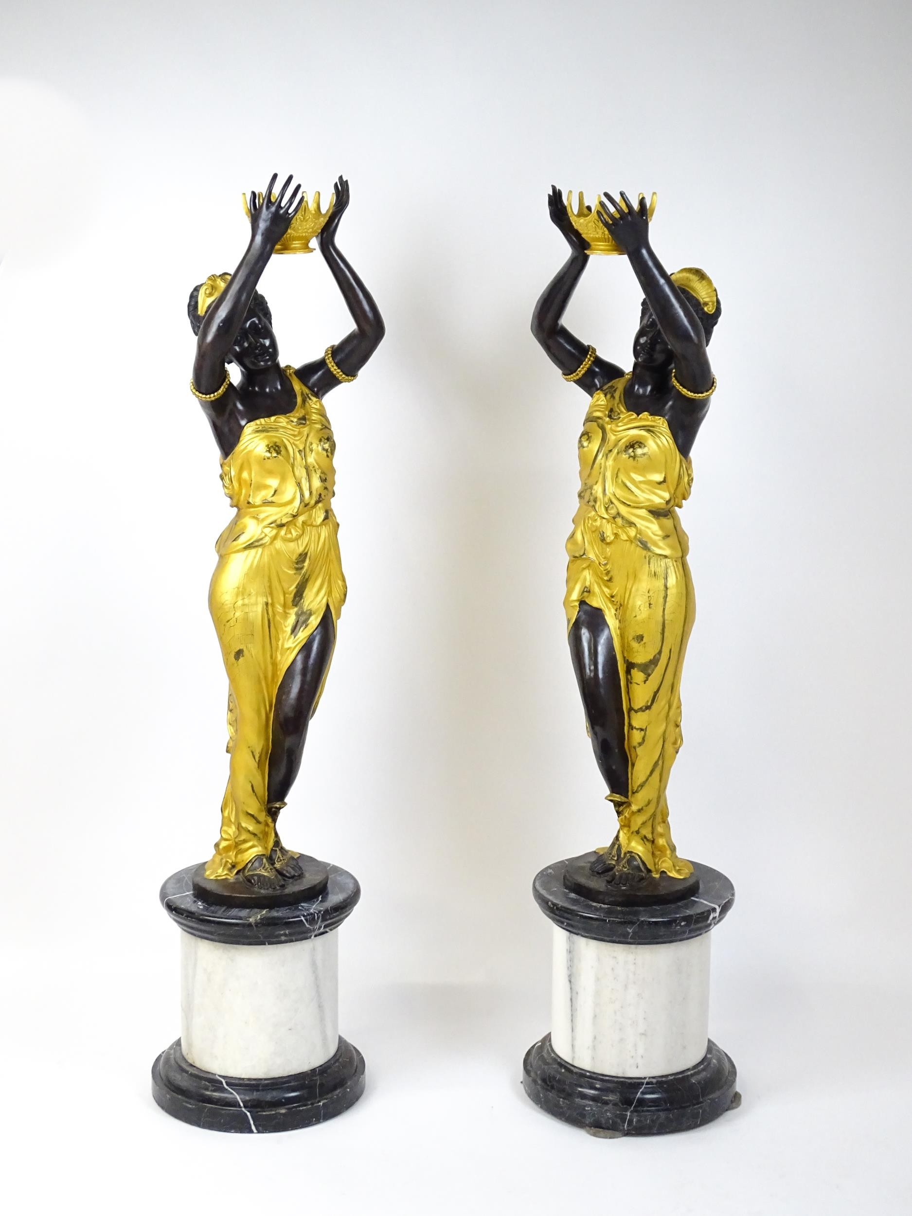 A pair of large cast bronze female blackamoor torcheres with gilt detail, raised on marble