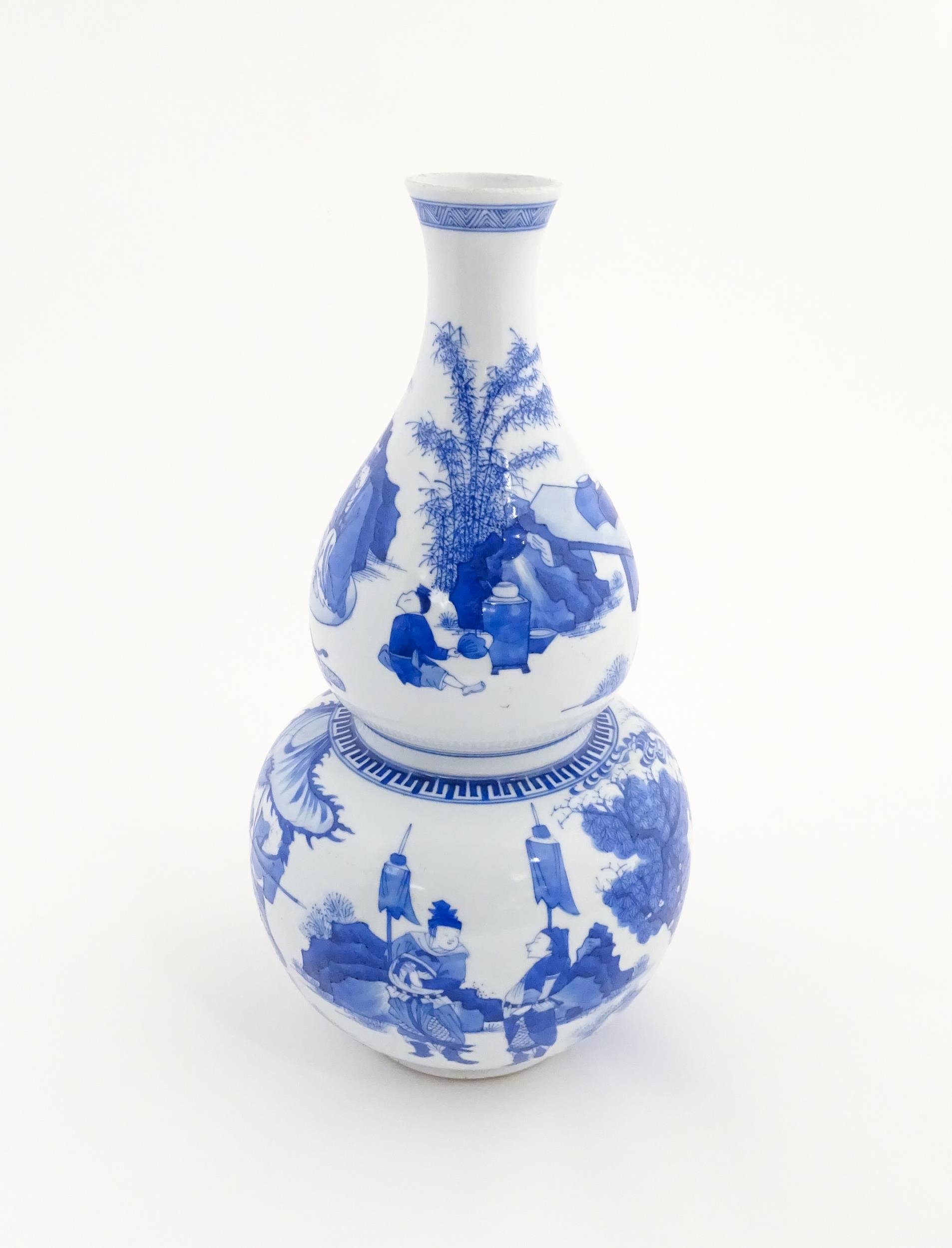 A Chinese blue and white double gourd vase decorated with figures in a landscape. Approx. 16 1/4"