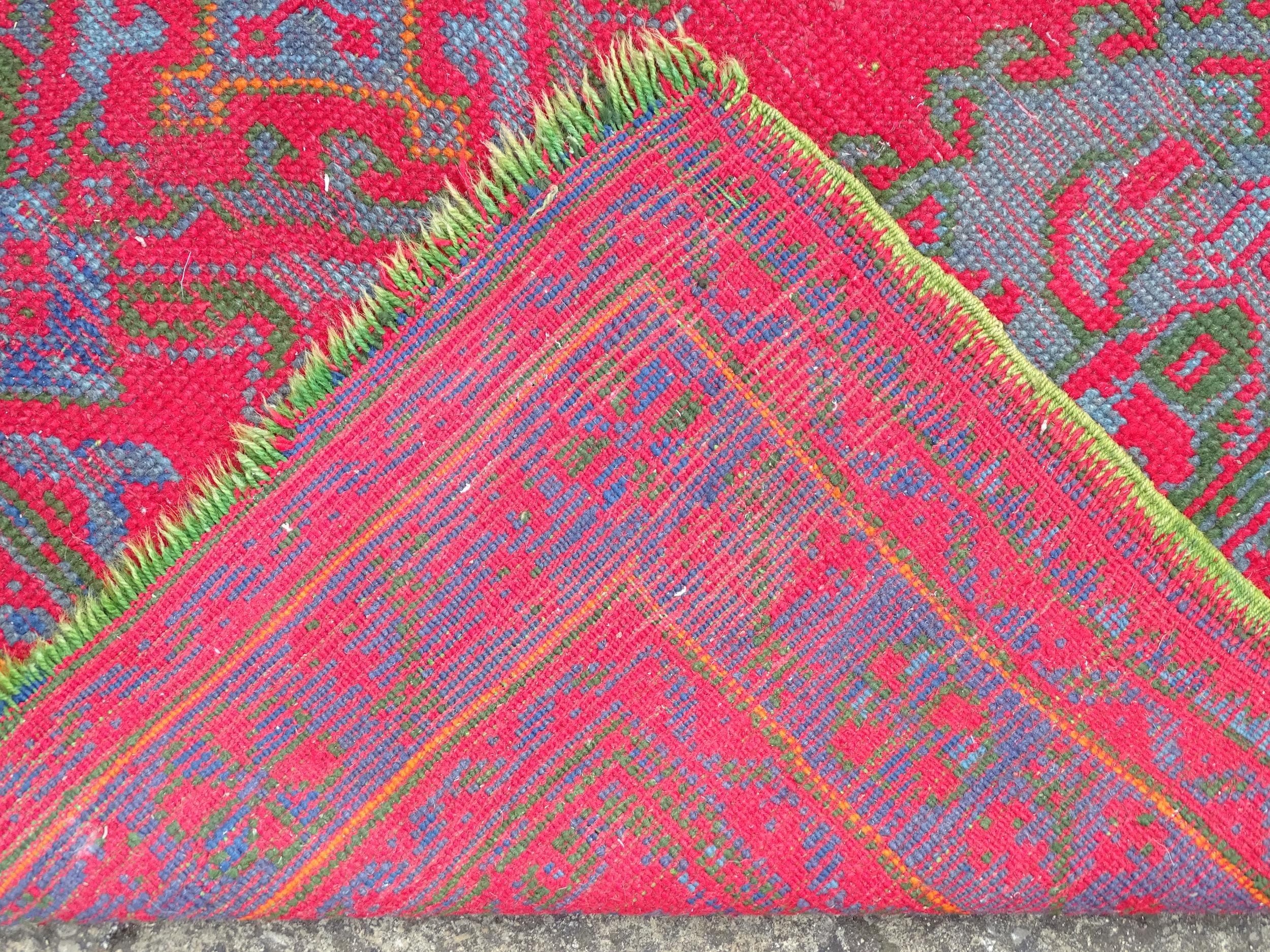 Carpet / Rug : A red ground rug decorated with floral, foliate and geometric detail worked in blue - Image 2 of 7