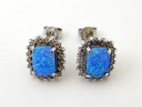 A pair of white metal stud earrings set with central opal bordered by white stones. Approx. 1/2"