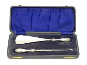 A cased silver handled shoe horn and button hook with bow and swag detail, hallmarked Birmingham