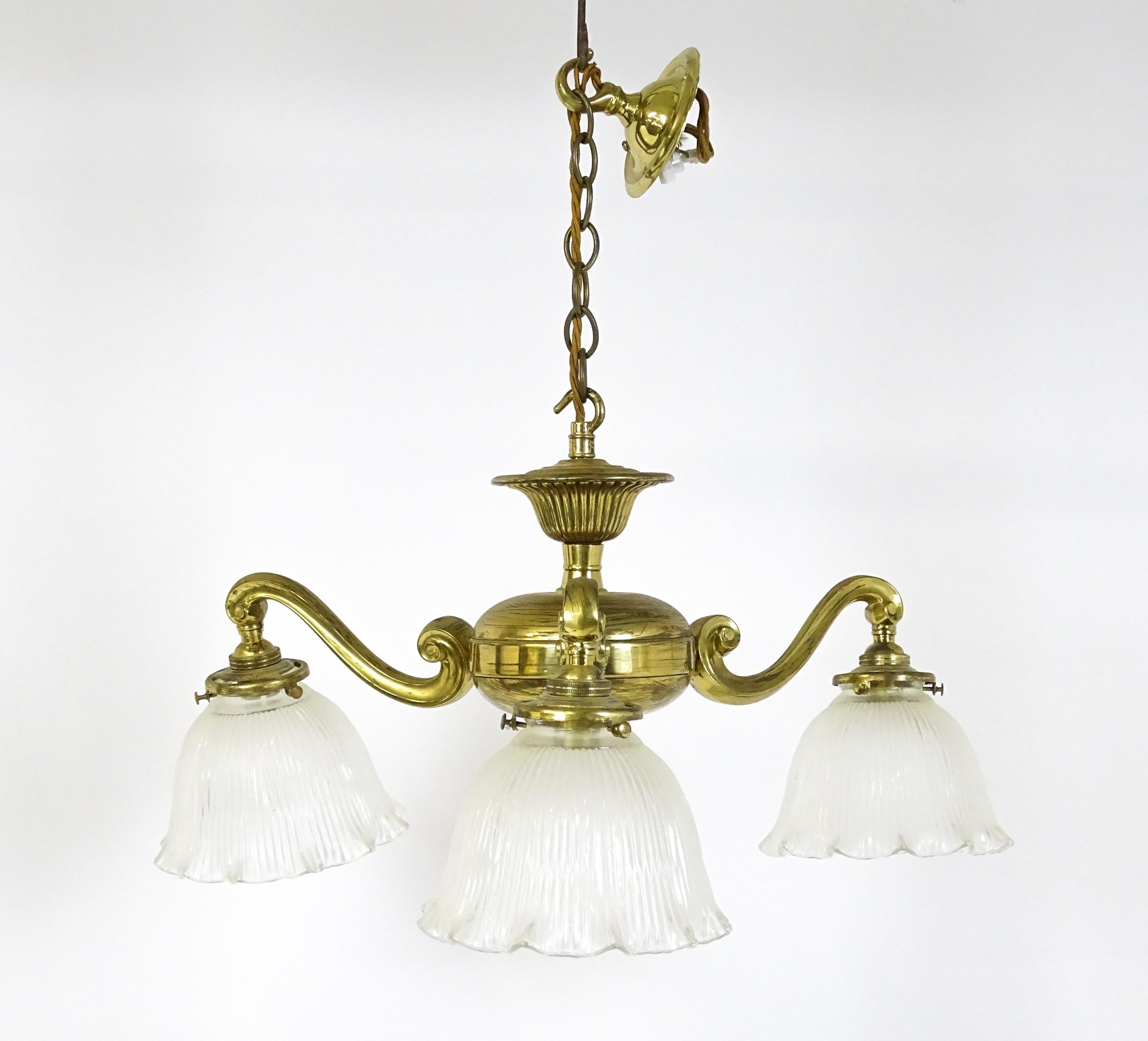 A pair of brass pendant lights having three scrolling branches with three holophane shades. - Image 2 of 16