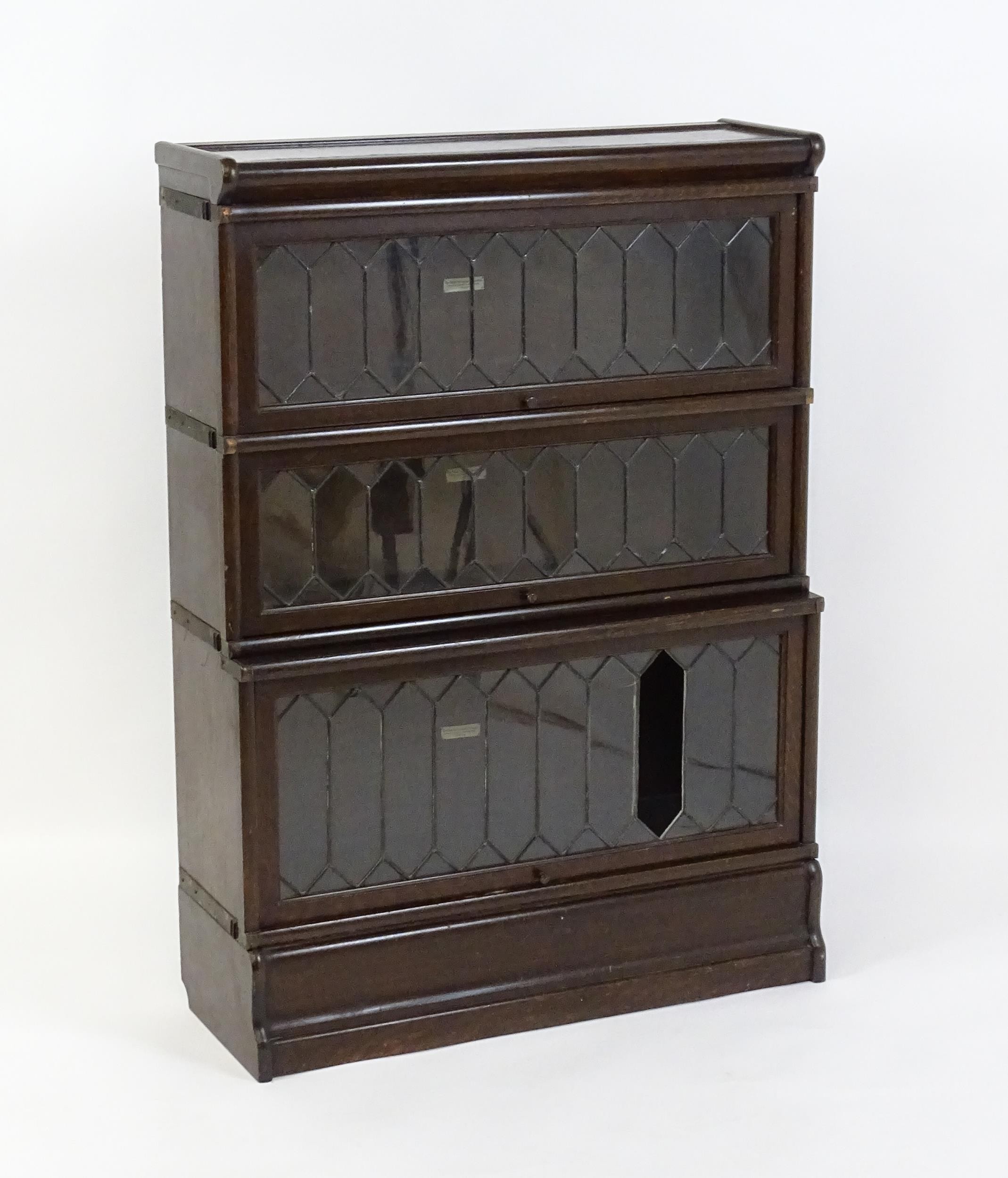 An early / mid 20thC oak Globe Wernicke bookcase with three glazed tiers above a shaped base. 34"