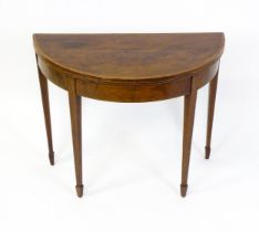 A late Georgian mahogany demi lune card table with a crossbanded top above four tapering legs