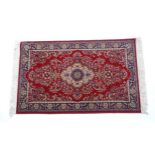 Carpet / Rug : A red ground rug with central cream and blue vignette, decorated with floral and