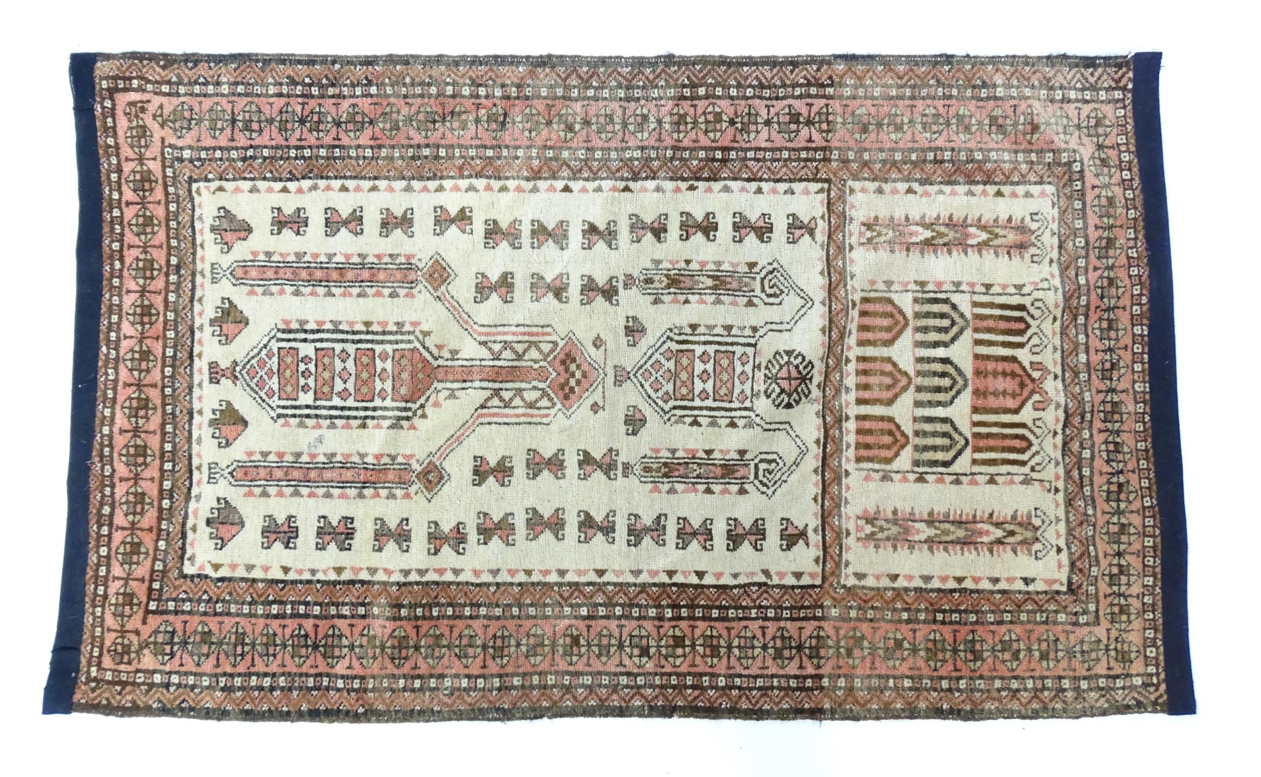 Carpet / Rug: A beige ground rug with repeated motifs worked in salmon pink, brown and beige, with