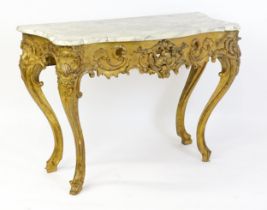 A 19thC marble topped table with a gesso and giltwood moulded base, decorated with shells,