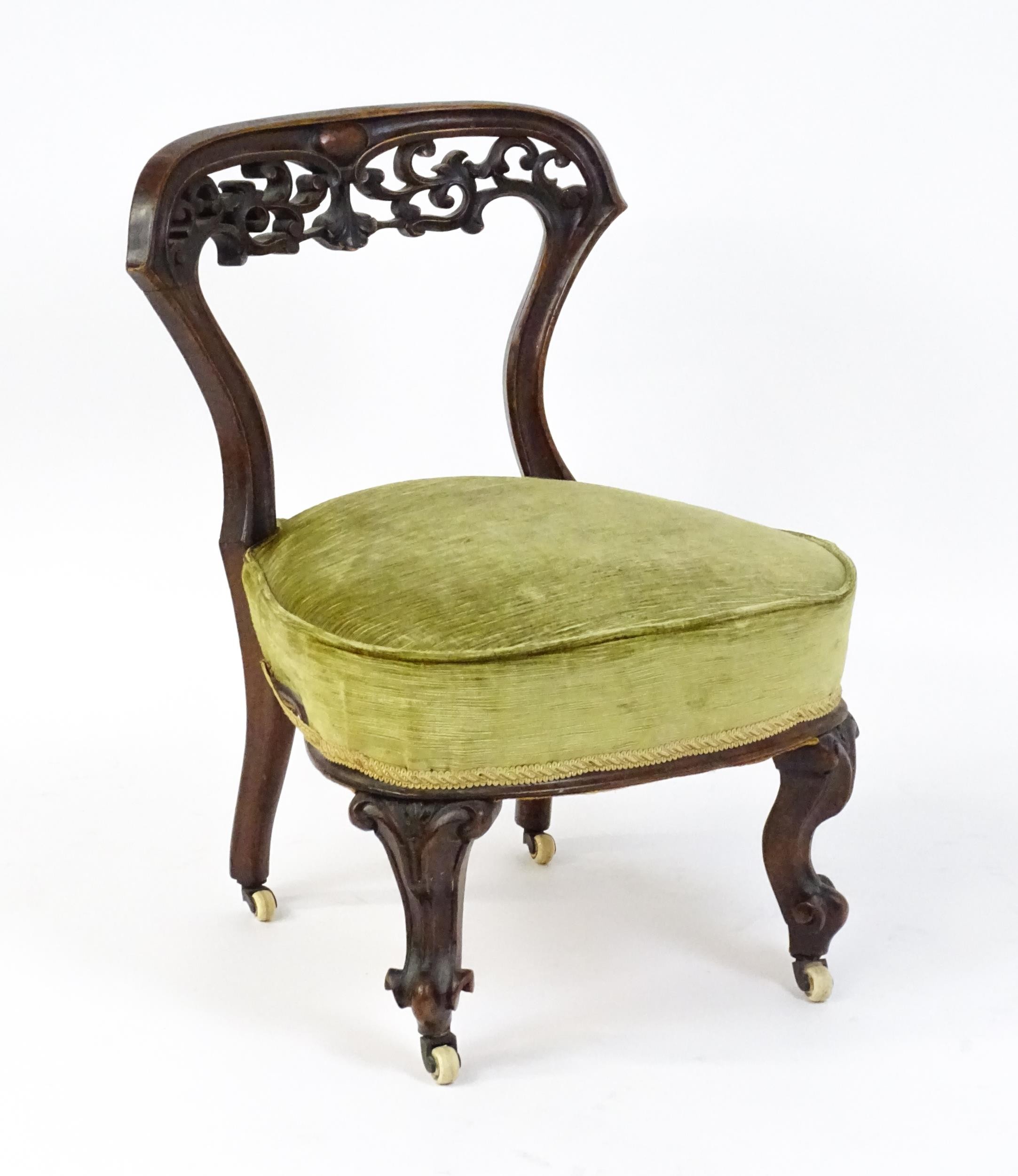 A mid / late 19thC mahogany nursing chair with a pierced, carved floral top rail above moulded