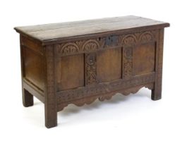 An early 18thC oak coffer of peg jointed construction, with a hinged lid and a carved, panelled