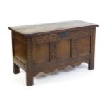 An early 18thC oak coffer of peg jointed construction, with a hinged lid and a carved, panelled