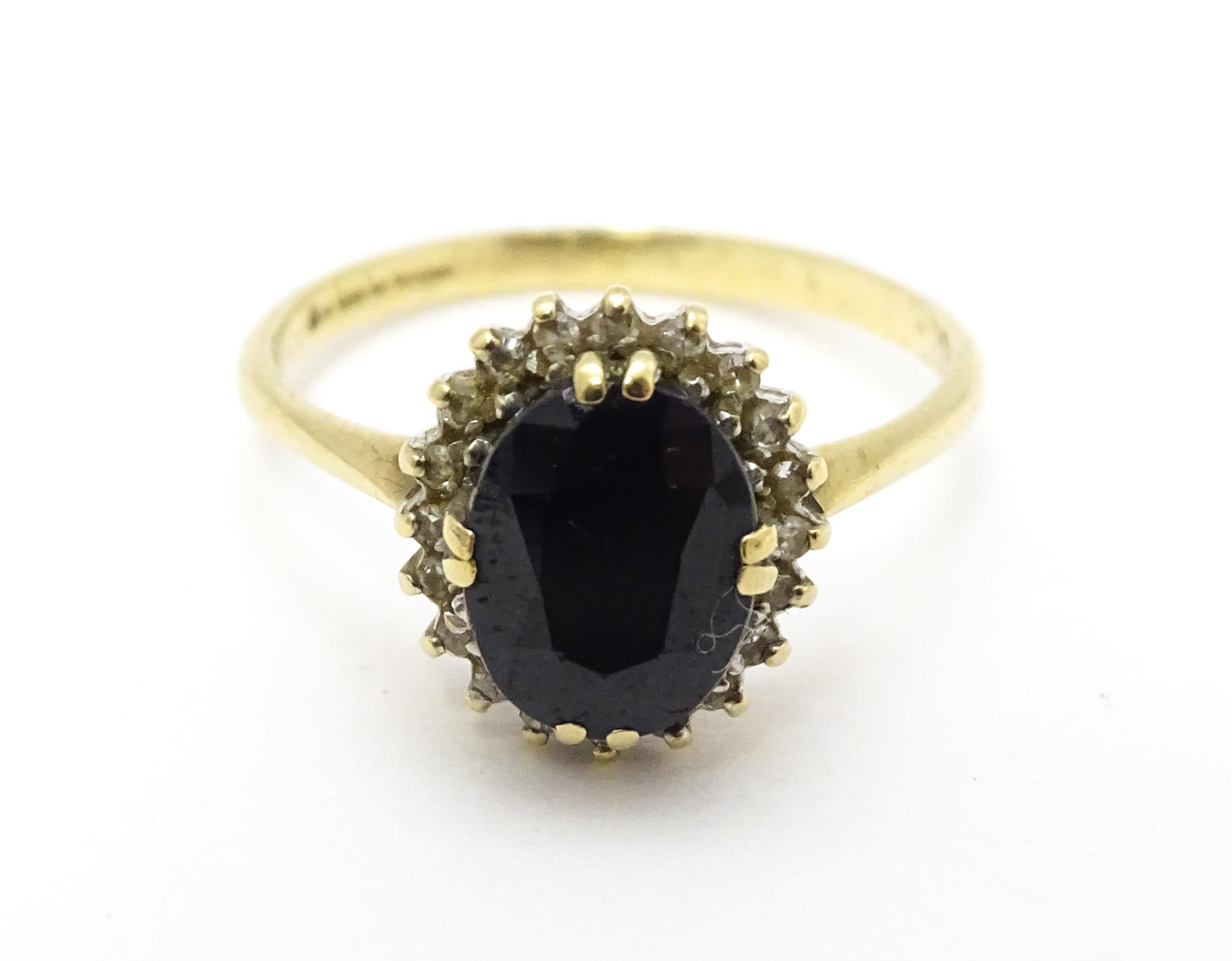 A 9ct gold ring set with central sapphire bordered by diamonds. Ring size approx. P Please Note - we