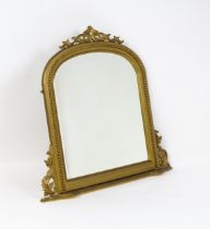 A modern mahogany mirror with a gilt finish, surmounted by a pierced, floral moulding and having