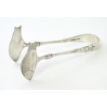 Victorian silver sardine servers of tong form with engraved decoration to the fish formed grips.