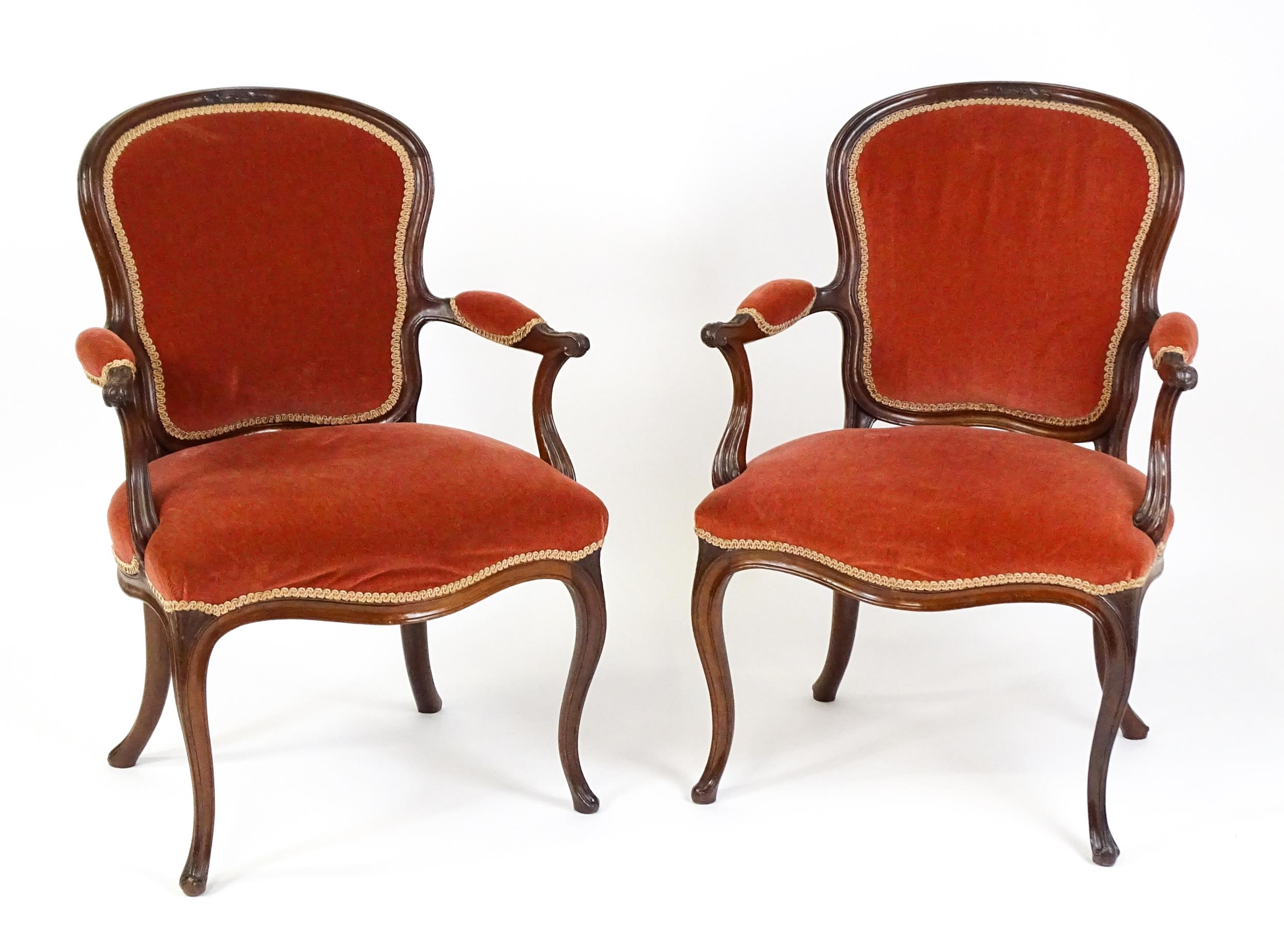 A pair of 19thC fauteuil armchairs with a carved cresting rail and arms raised on shaped seat