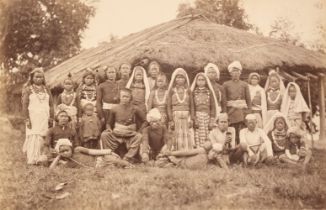 India. A large group of Bhootea and Nepalese tea plantation workers posing outside a thatched