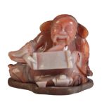 A CHINESE CARVED AGATE FIGURE OF A RECLINING SCRIBE