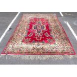 A ROSE GROUND KIRMAN STYLE CARPET WITH GREEN BORDER