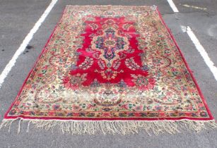 A ROSE GROUND KIRMAN STYLE CARPET WITH GREEN BORDER