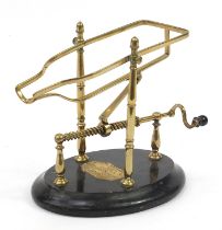 Farrow & Jackson of London & Paris, 19th century brass mechanical wine cradle with an ebonised base,