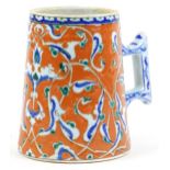 Turkish Ottoman Iznik tankard with tapering body hand painted with stylised flowers, 15.5cm high :