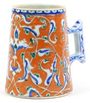 Turkish Ottoman Iznik tankard with tapering body hand painted with stylised flowers, 15.5cm high :
