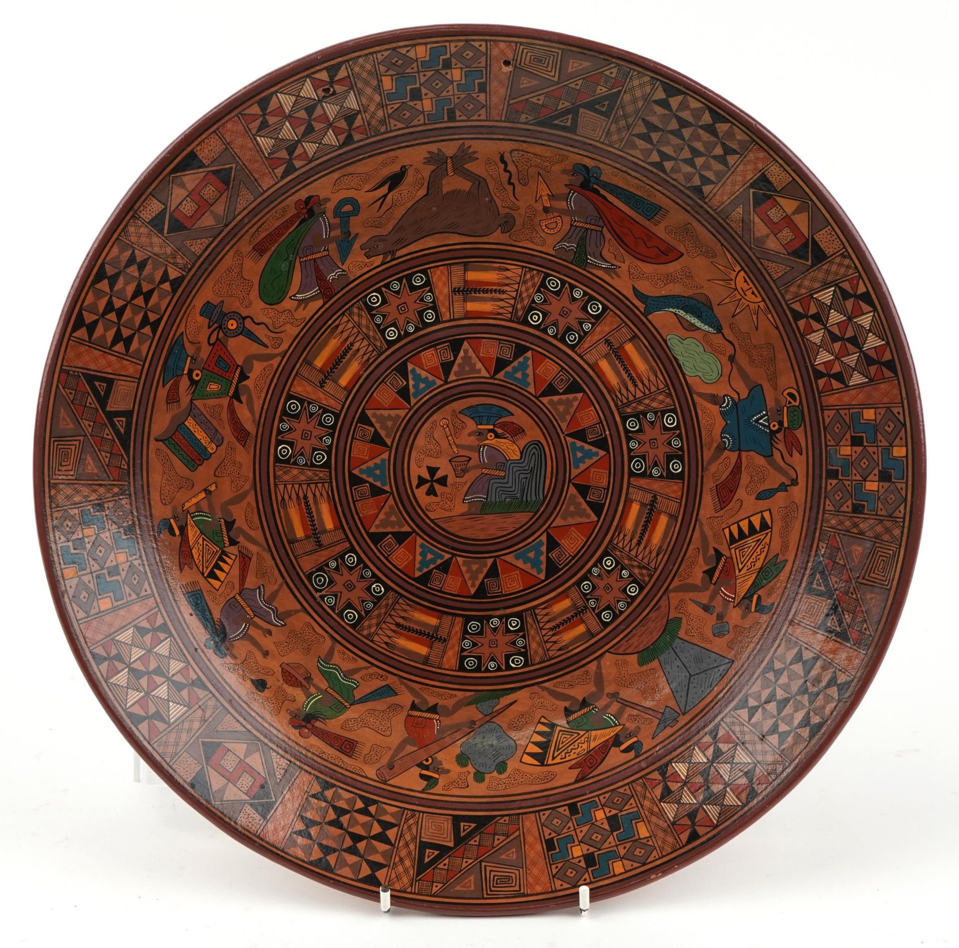 Peruvian terracotta charger hand painted with mythical figures and animals, inscribed Chinchero