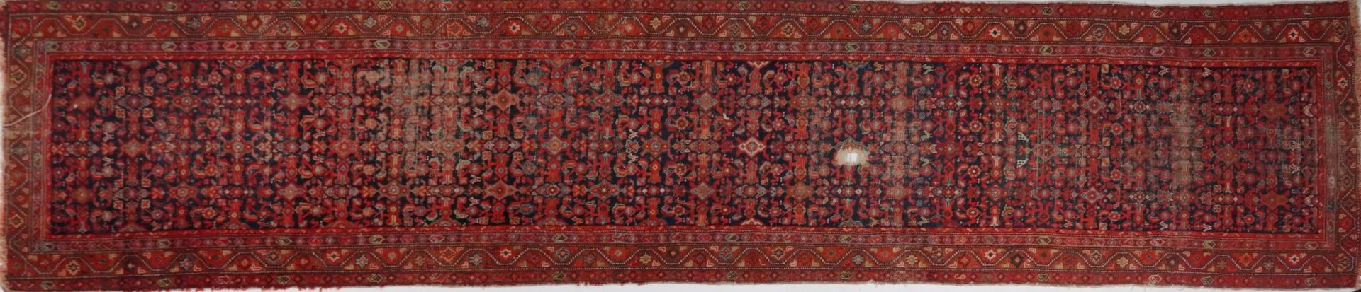 Rectangular Persian red and blue ground carpet runner having an allover floral repeat central field,