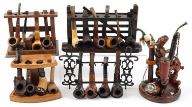 Twenty one vintage tobacco smoking pipes, some European, arranged in five pipe racks, one carved