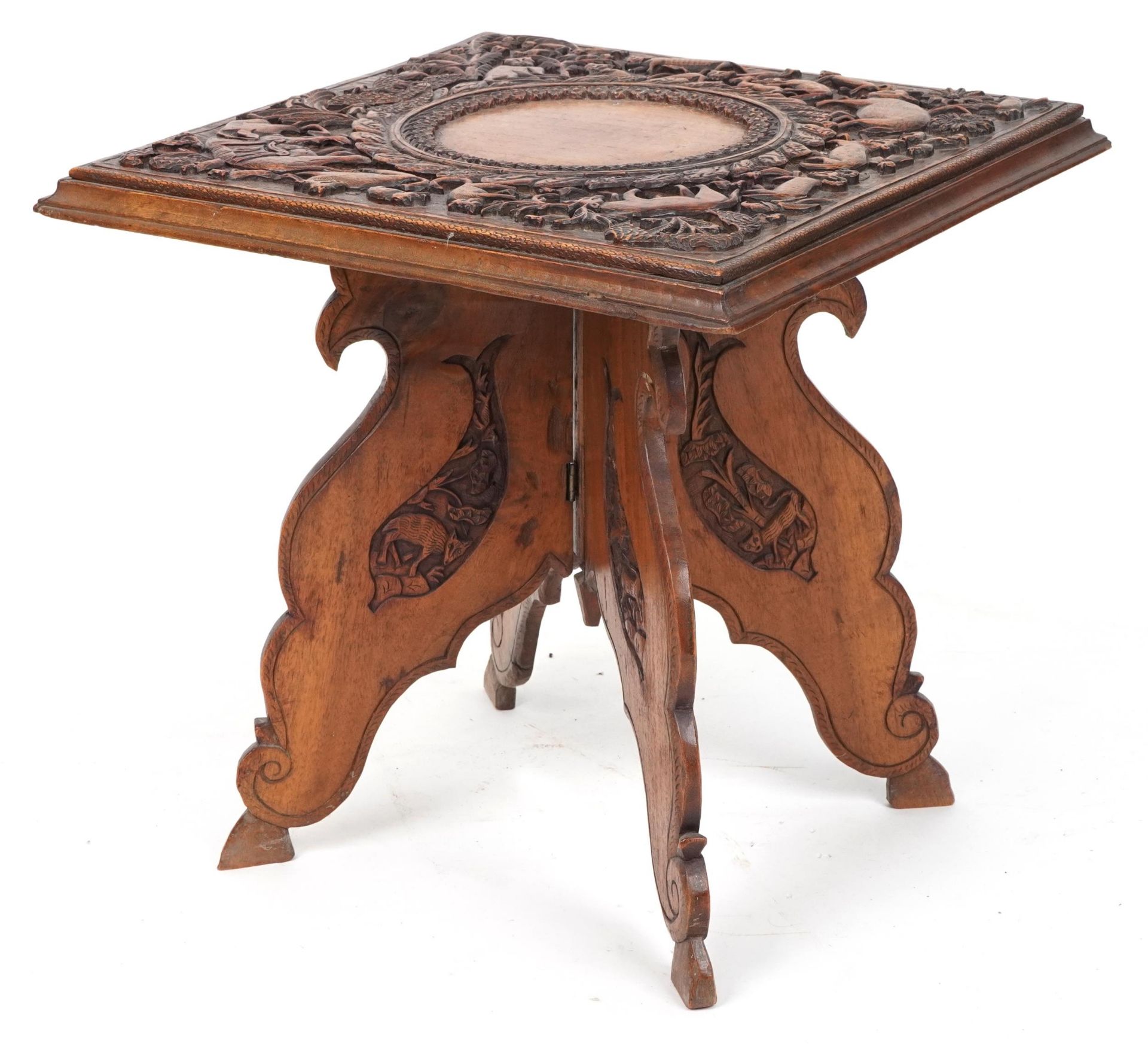 Anglo Indian hardwood folding side table, finely and deeply carved with an elephant and wild animals