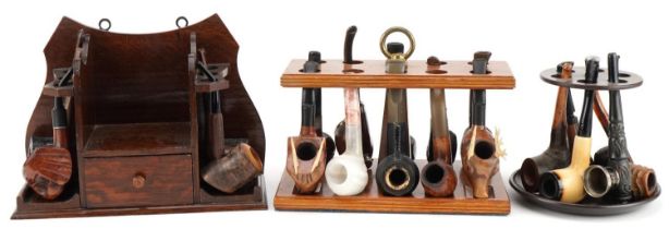 Twenty tobacco smoking pipes, some briar, arranged in three pipe racks including Dr Plumb and Kay