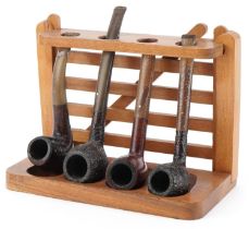 Four Dunhill briar tobacco smoking pipes arranged in a gate design pipe rack including Shell