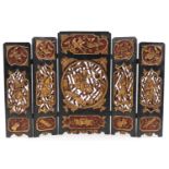 Chinese partially gilt red and black lacquered wood five fold screen pierced and carved with