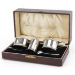 William Neale & Son Ltd, George V silver three piece cruet set with blue glass liners housed in a