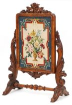 Victorian walnut screen carved with foliage housing a needlepoint tapestry of flowers in an urn,