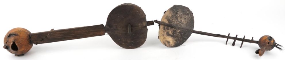 Two tribal interest African wooden animal hide musical instruments, the largest 68.5cm in length :